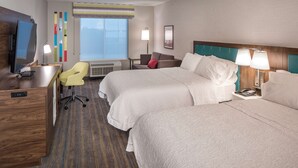 A hotel room with two beds, a desk, a chair, a TV, and a window with blinds. - Hampton Inn Hastings (Hastings)