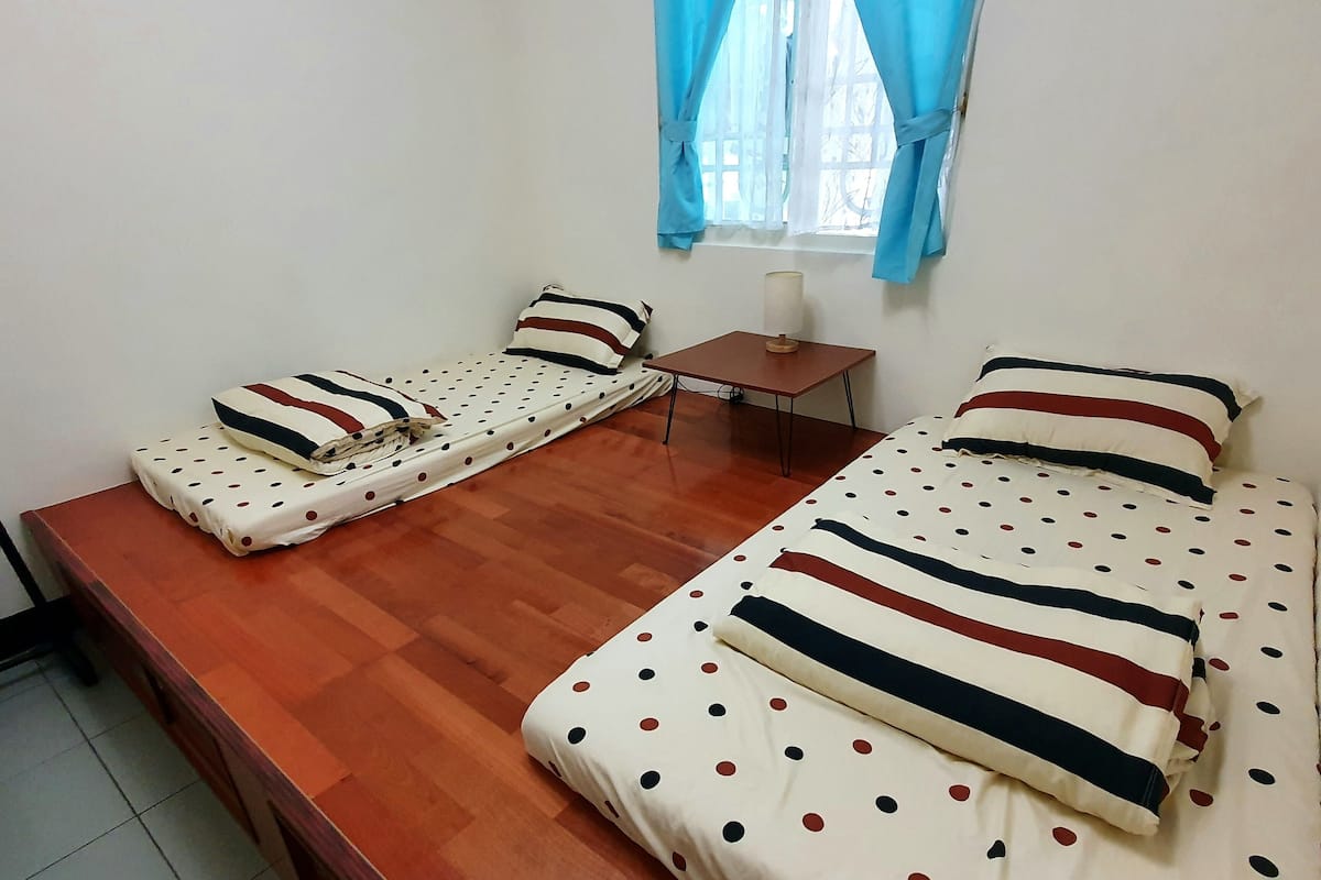 A room with two beds, a small table, and a window with curtains.