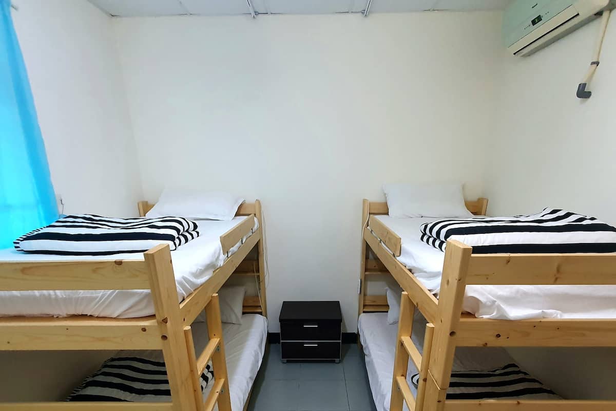A room with two bunk beds, a small black storage unit, and a wall-mounted air conditioner.