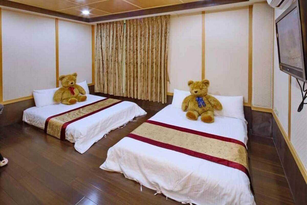 A hotel room with two beds, each with a teddy bear on the pillows.