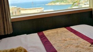 A hotel room with a large window offering a view of the sea and a distant coastline. - Shangrila (Dongyin Town)