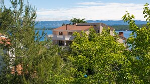 A two-story building with a balcony, surrounded by trees and overlooking a body of water with mountains in the background. - Summer House Magdalena (Malinska-Dubasnica)