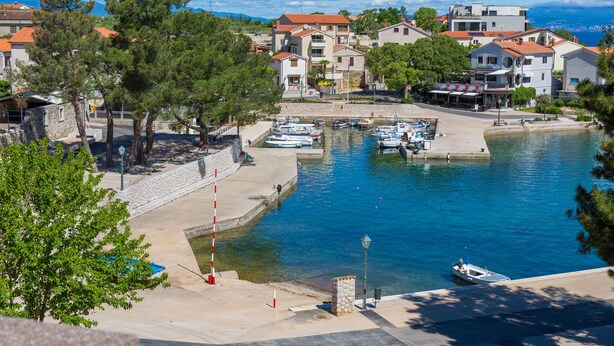 A marina with boats docked, surrounded by buildings with red roofs and trees. - Summer House Magdalena (Malinska-Dubasnica)