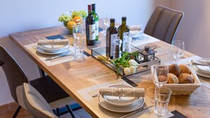 A dining table set with plates, cutlery, wine bottles, glasses, and a basket of bread. - Summer House Magdalena (Malinska-Dubasnica)
