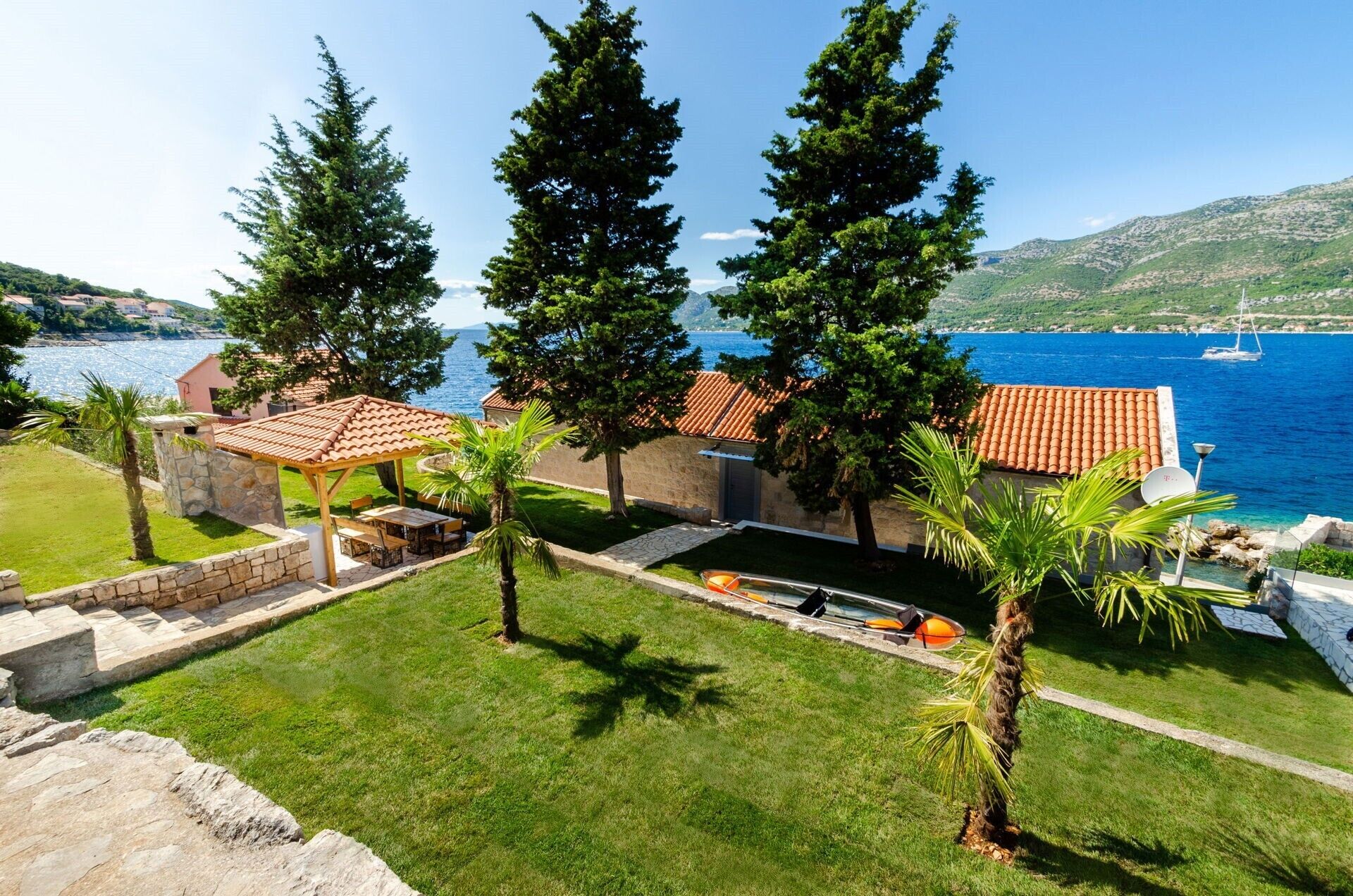 Une propriété située sur la côte, dotée d’une terrasse, de murs en pierre et offrant une vue sur la mer.