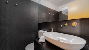 A modern bathroom with a large white sink, dark tiled walls, and a mirror with a gold frame. - Nomad's Family - 2BDR Spacious Apartment Gaia (Vila Nova de Gaia)