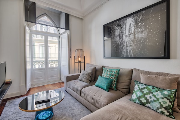 Un salon avec un canapé beige, une table basse en verre et un tableau encadré accroché au mur.