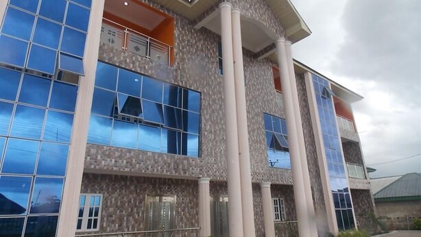 A multi-story building with large windows and columns. - Amba Hotels Limited (Yenagoa)
