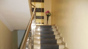 A staircase with a metal handrail and a vase of flowers at the top. - Amba Hotels Limited (Yenagoa)