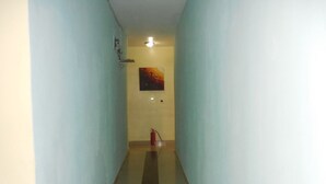 A narrow hallway with light blue walls and a dark floor. A fire extinguisher is mounted on the wall. - Amba Hotels Limited (Yenagoa)