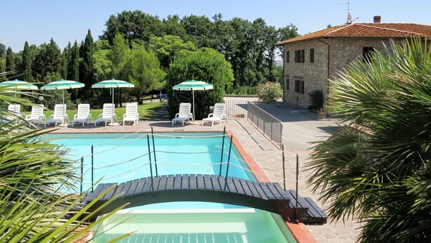 A swimming pool with lounge chairs and umbrellas, surrounded by trees and a stone building. - Cosy apartment in villa for 4 guests with WIFI, pool, terrace and pets allowed (Terricciola)