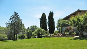 A lush green lawn with a stone building featuring an arched entrance and a balcony. - Beautiful apartment in villa for 7 people with pool, WIFI, TV, terrace and pets allowed (La Casetta)