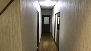 A narrow hallway with wooden walls and a wooden floor, leading to a door at the end.