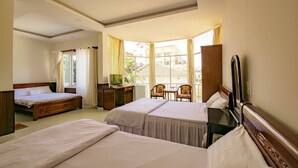 Een hotelkamer met twee bedden, een bureau, een stoel en een groot raam met gordijnen.