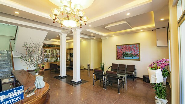 Een hotel receptie met een marmeren receptiebalie, een kroonluchter, zitplaatsen en een schilderij aan de muur.