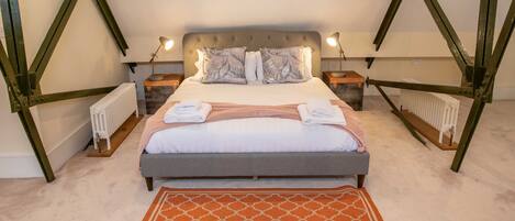 Une chambre à coucher avec un lit, deux tables de chevet, un radiateur et un tapis à motifs.