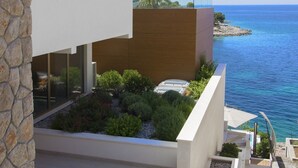 Un edificio moderno con fachada de piedra, terraza de madera y vista al mar.