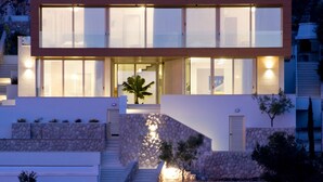 Una casa moderna de dos pisos con fachada de piedra, ventanas grandes y una escalera que conduce a la entrada.