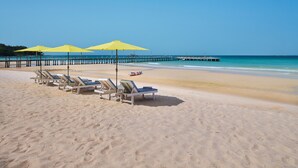 A beach with sun loungers and yellow umbrellas, a pier extending into the water, and clear skies. - Sandy Beach Bungalows by EHM (Koh Rong Sanloem)