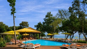 A pool area with lounge chairs and umbrellas, surrounded by trees and a clear sky. - Sandy Beach Bungalows by EHM (Koh Rong Sanloem)