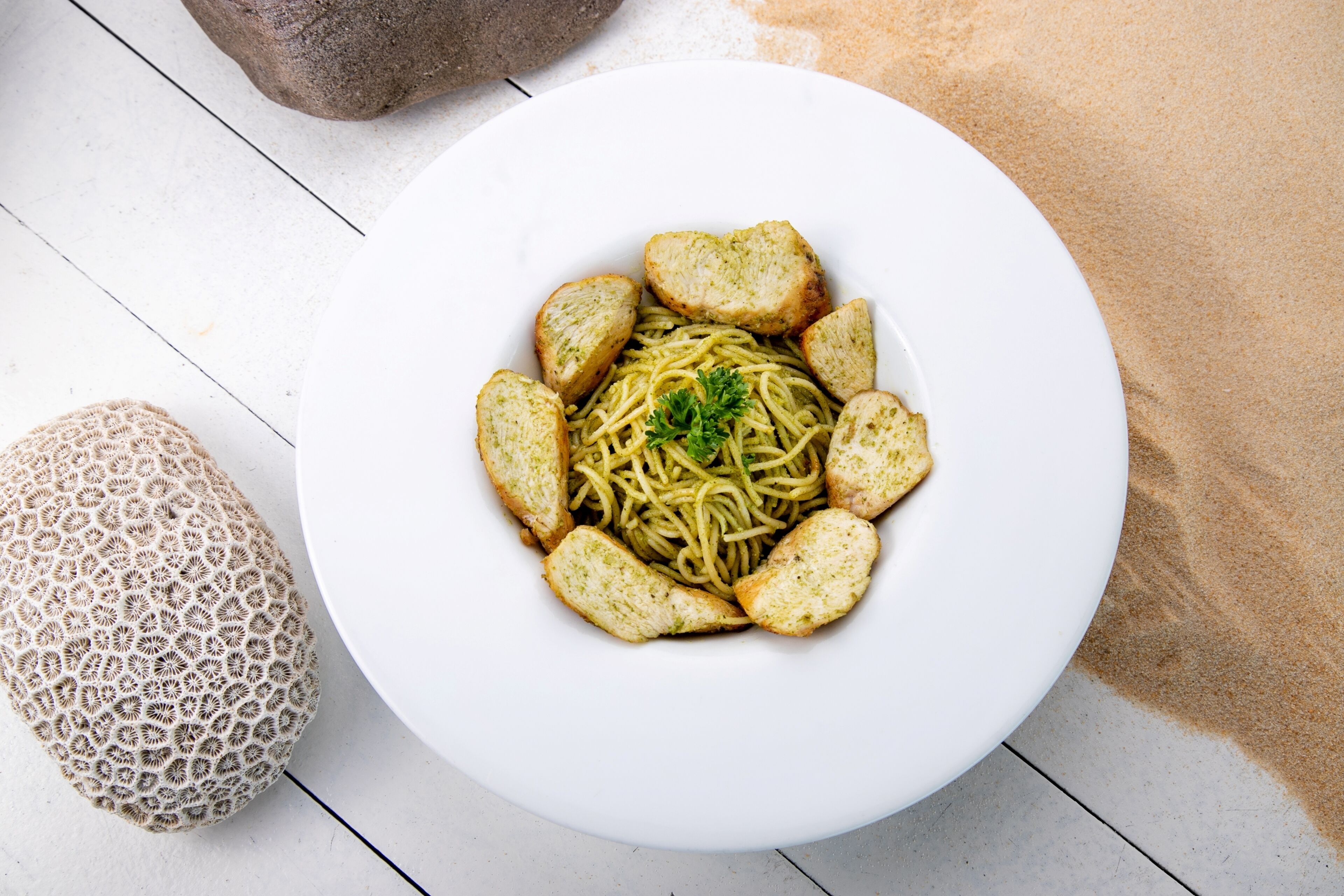 Une assiette blanche contenant des spaghettis et du pain, posée sur une surface blanche.