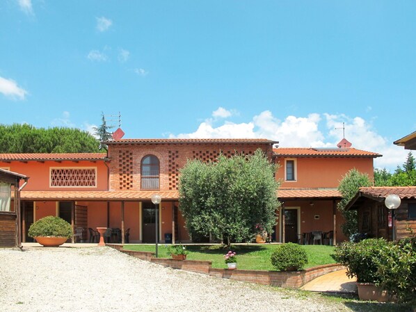 Traditional building with a central entrance, flanked by windows, set amidst a well-maintained lawn and potted plants.