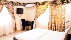 A hotel room with a bed, a desk, and an air conditioning unit. - Lantano Cottage (Lagos)