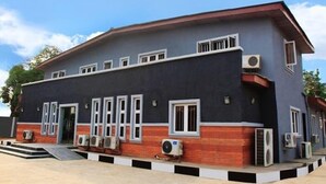 A two-story building with a flat roof, multiple windows, and air conditioning units. - Lantano Cottage (Lagos)