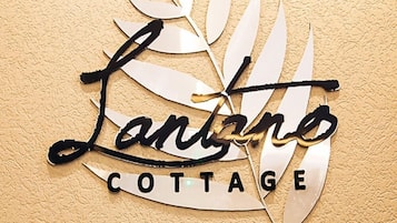 Et metalskilt med teksten "Lanaro Cottage" omgivet af bladformede figurer.