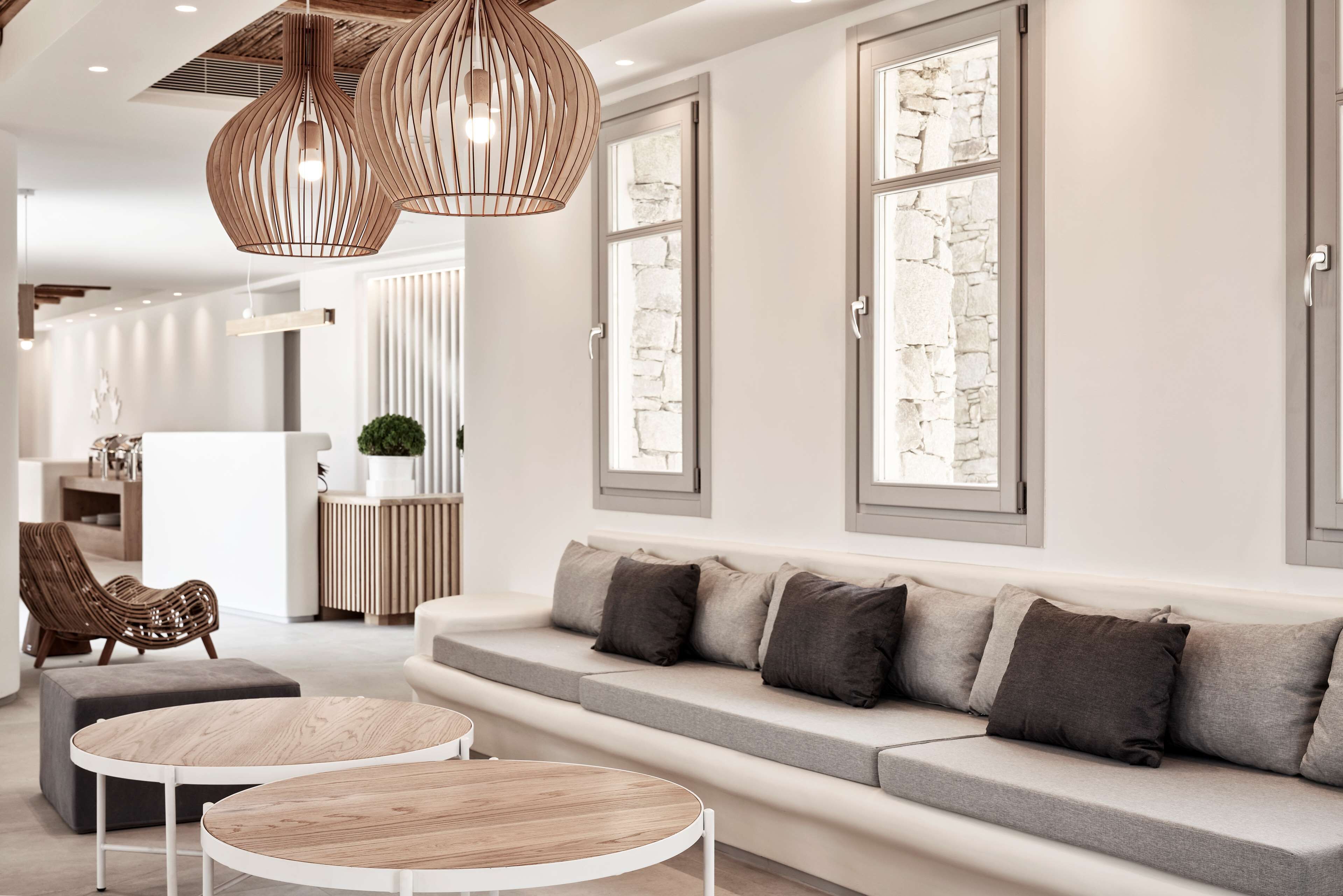 A modern living room with a grey sofa, two round wooden tables, and a wicker chair.