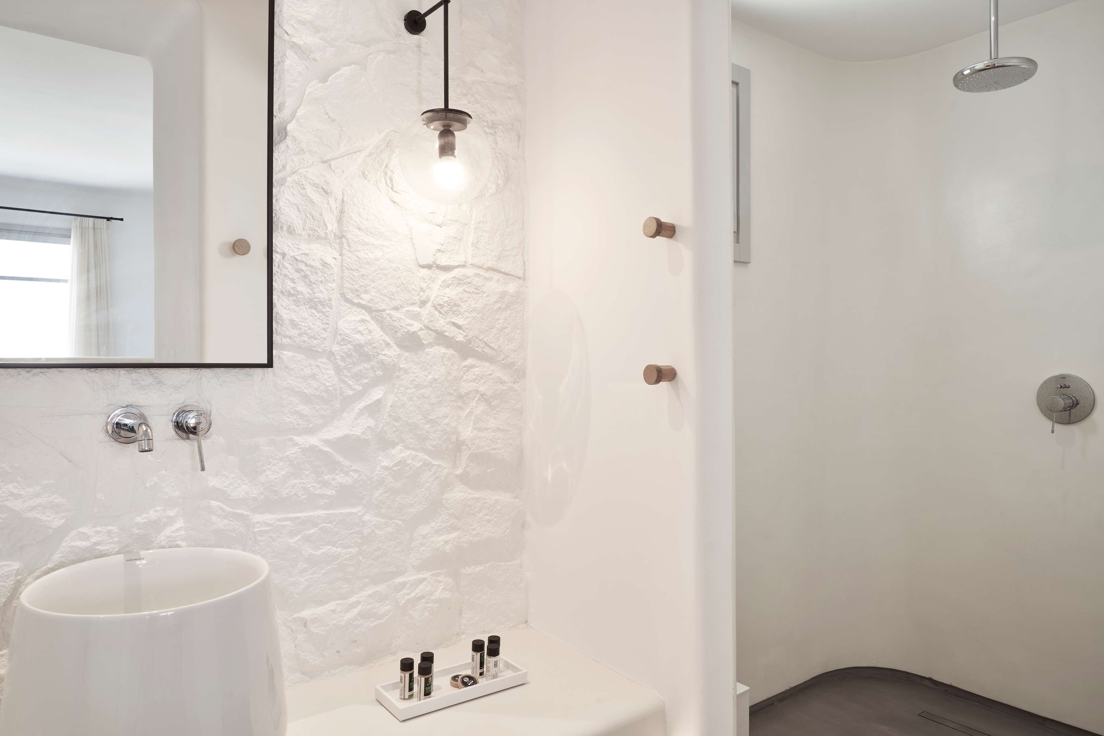 Ein modernes Badezimmer mit einer weißen Wand mit Struktur, einem großen weißen Waschbecken, einem Spiegel und einer Duschkabine.