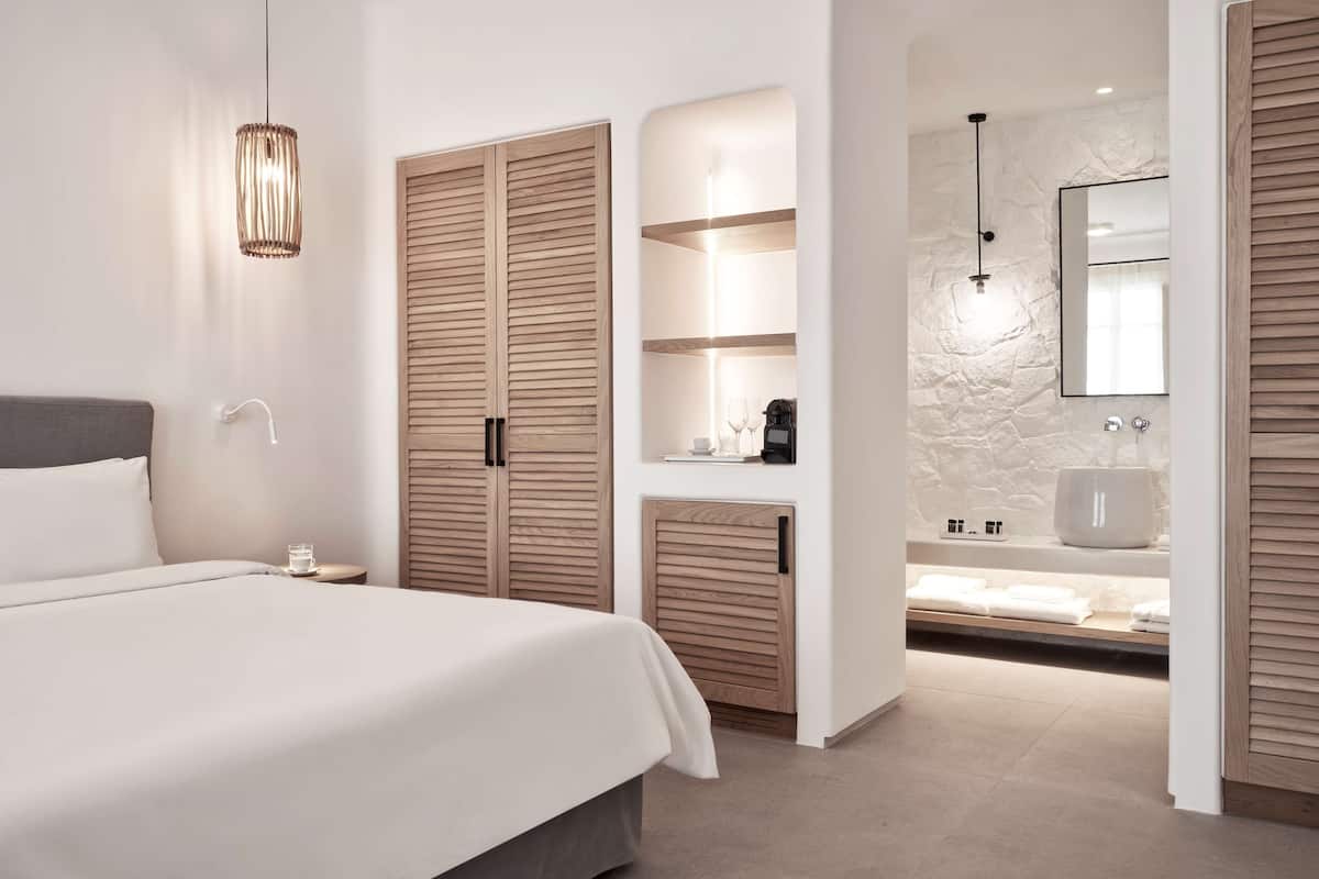 A modern bedroom with a large bed, a bedside table with a glass, and a wardrobe with sliding doors.