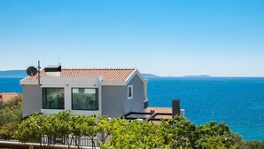Una casa moderna con techo de tejas, amplias ventanas y vista al mar.