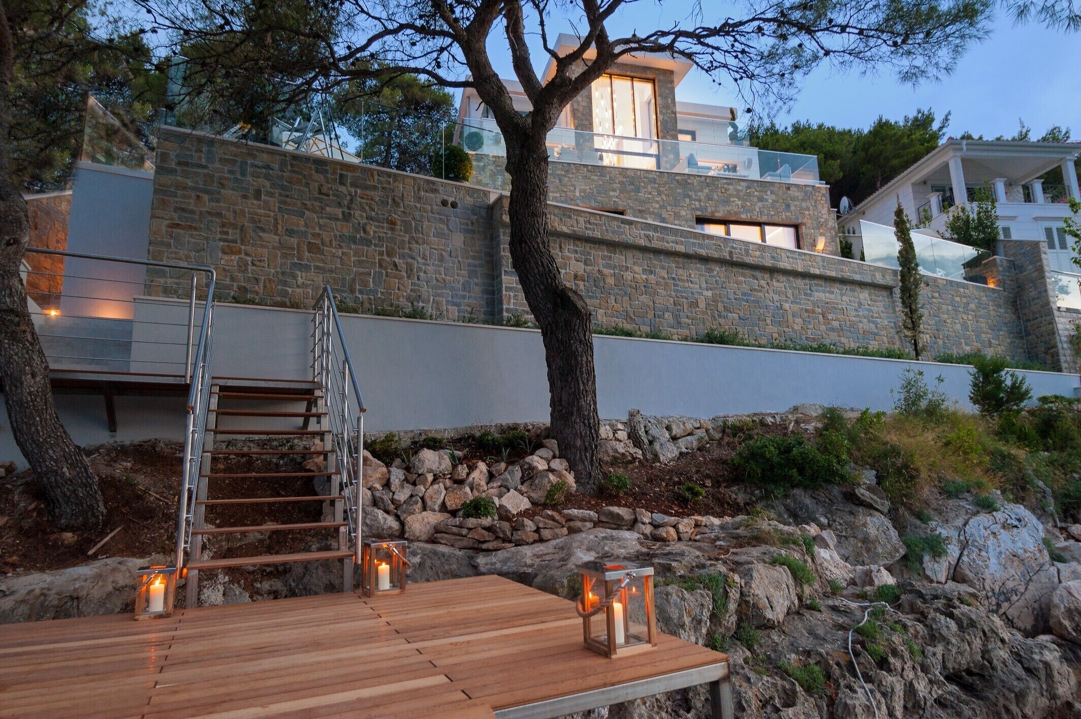 A wooden deck with a metal staircase leading up to a stone wall.