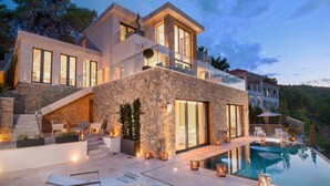 A modern house with a pool, outdoor seating, and a stone facade. - Luxury Villa Silent with Infinity Pool (Selca)