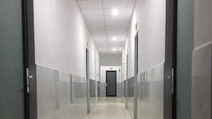 A long, narrow hallway with doors on both sides, leading to a dark door at the end. - Mai Tuan Pham Hung Hotel (Hoa Thanh)