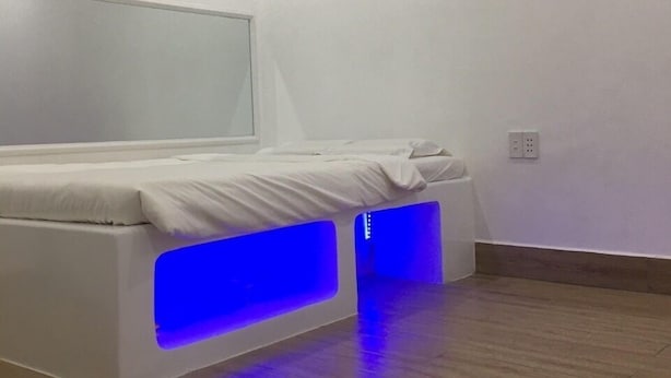 A modern bedroom with a bed, built-in lighting, an air conditioning unit, and a wall-mounted control panel. - Mai Tuan Pham Hung Hotel (Hoa Thanh)
