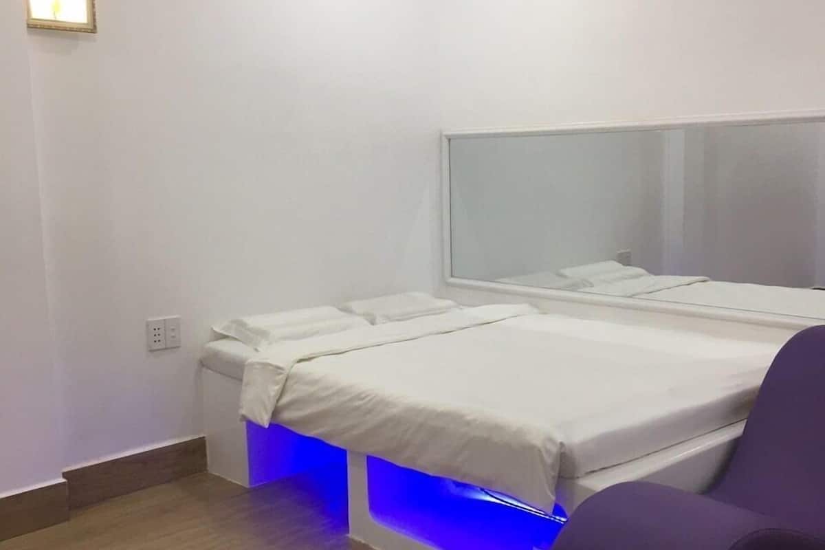 A modern bedroom with a bed, a bedside table, a chair, and an air conditioning unit.