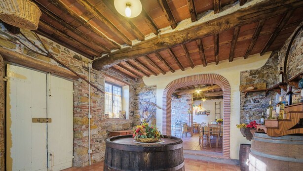 A rustic interior with exposed brick walls, wooden beams, and a large barrel in the center. - Nice apartment in villa for 2 people with pool, A/C, WIFI, TV and terrace (Lucca)