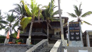 A hotel with a stone staircase leading to a thatched-roof building, surrounded by palm trees. - Jazzybeach Hotel (Nosy Be)