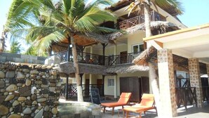 A resort with a stone wall, palm trees, and a pool area with lounge chairs. - Jazzybeach Hotel (Nosy Be)