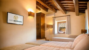 A hotel room with two beds, a wooden ceiling, a wall-mounted sign, and a window with a view. - Borgo Sant'Apollinare (Marsciano)