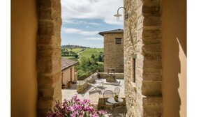 A stone building with a view of a green landscape through an archway. - Borgo Sant'Apollinare (Marsciano)