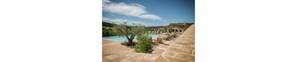 A pool area with a clear view of the surrounding landscape, a stone pathway, and a building in the background.