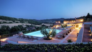 A poolside area with a pool, lounge chairs, and a building with outdoor lighting. - Borgo Sant'Apollinare (Marsciano)