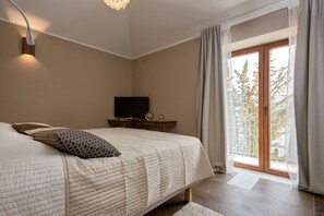 A bedroom with a bed, a television, and a view of the outdoors.