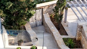 A staircase with stone walls and a metal gate, surrounded by trees and potted plants. - Luxury Villa Hvar Enigma with Pool (Jelsa)