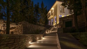A stone staircase leading to a multi-story building with a balcony, surrounded by trees and stone walls. - Luxury Villa Hvar Enigma with Pool (Jelsa)