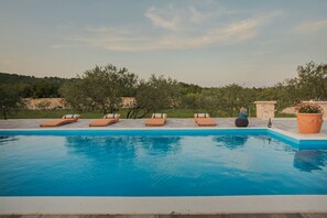 Une piscine avec des chaises longues et un mur de pierre en arrière-plan.