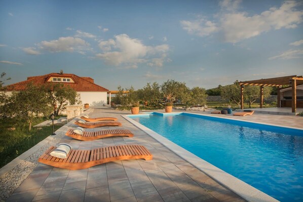Une piscine avec des chaises longues et une pergola.